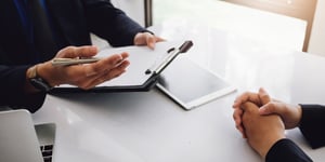 A closeup of hands and a document folder indicating an interview or a business conversation